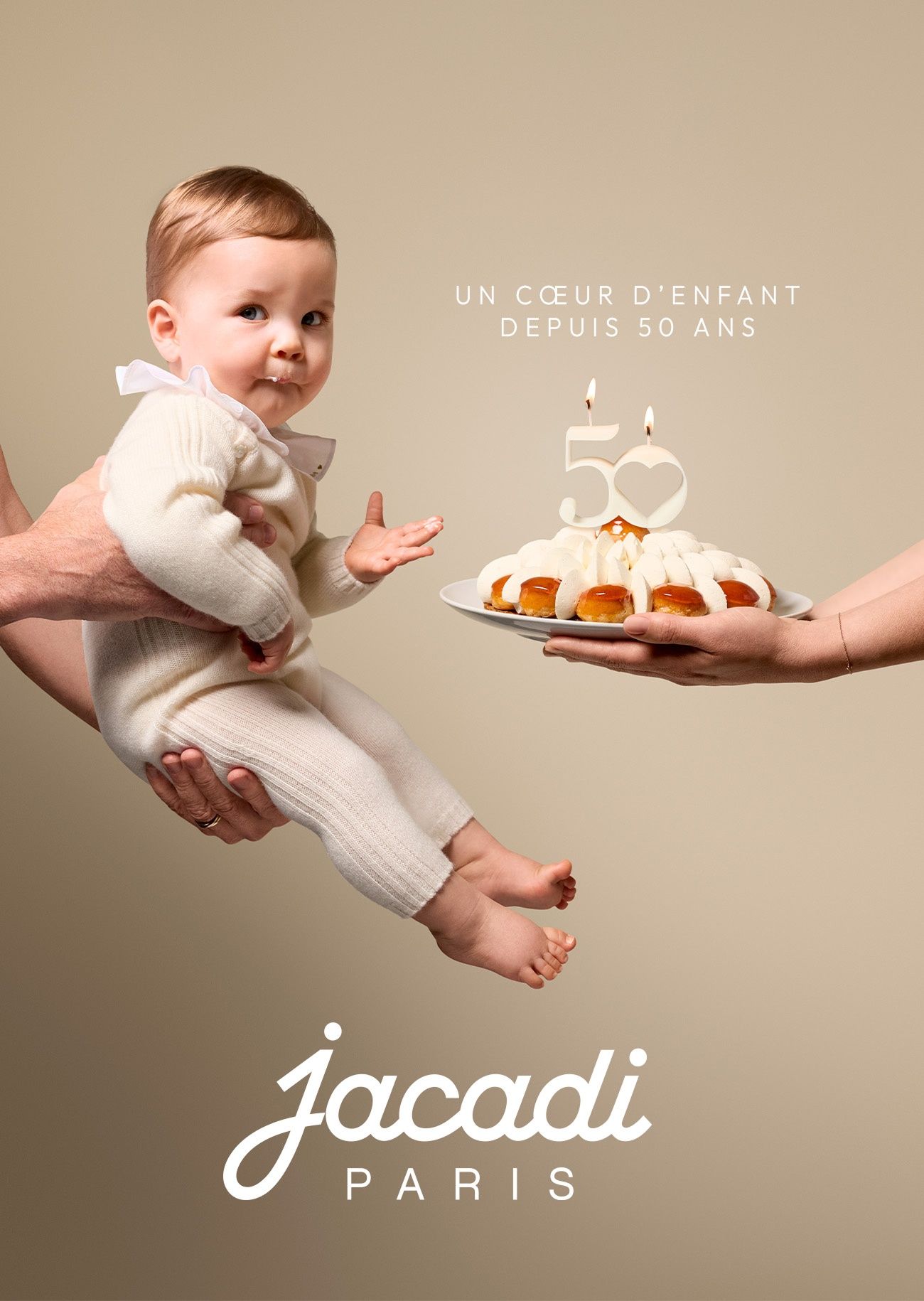 Ein Baby in einem Kaschmir-Set, das den Geburtstagskuchen von Jacadi Paris probiert