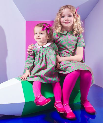 Zwei Mädchen, mit einem Liberty-Kleid mit rosafarbenen Riemchenschuhe.